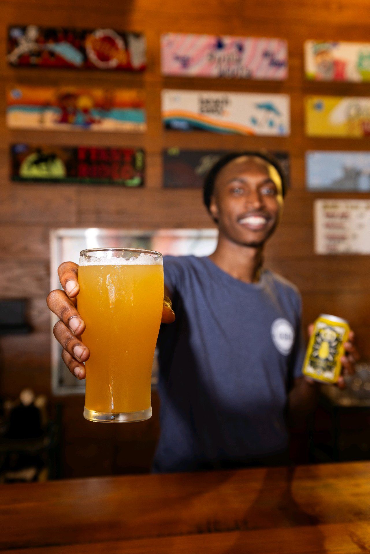A bartender presenting a golden beer in the taproom