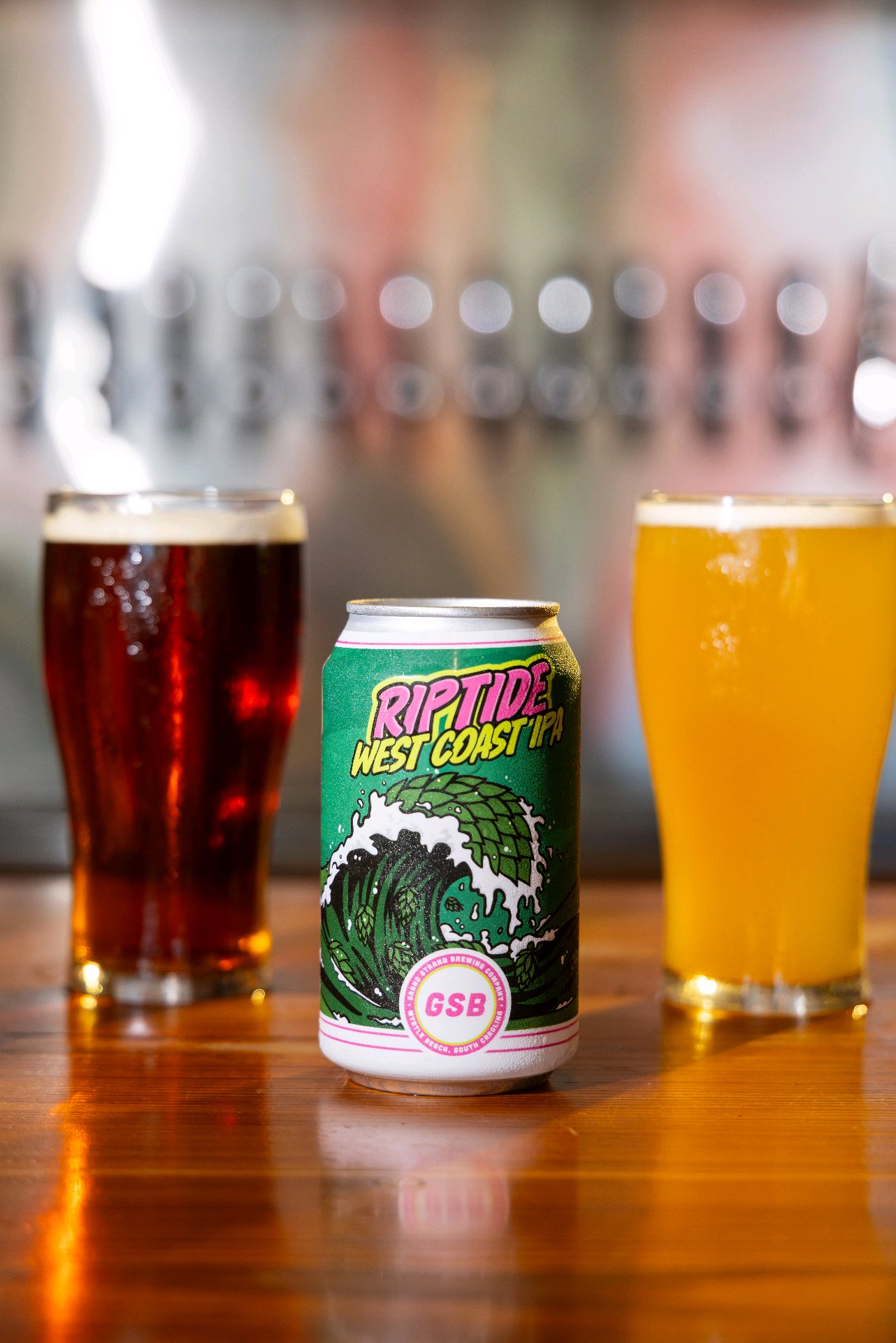 A Riptide West Coast IPA can framed by two pints
