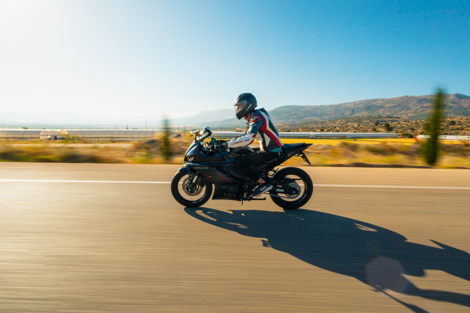 Motorcyclist riding an open road with hills in the distance