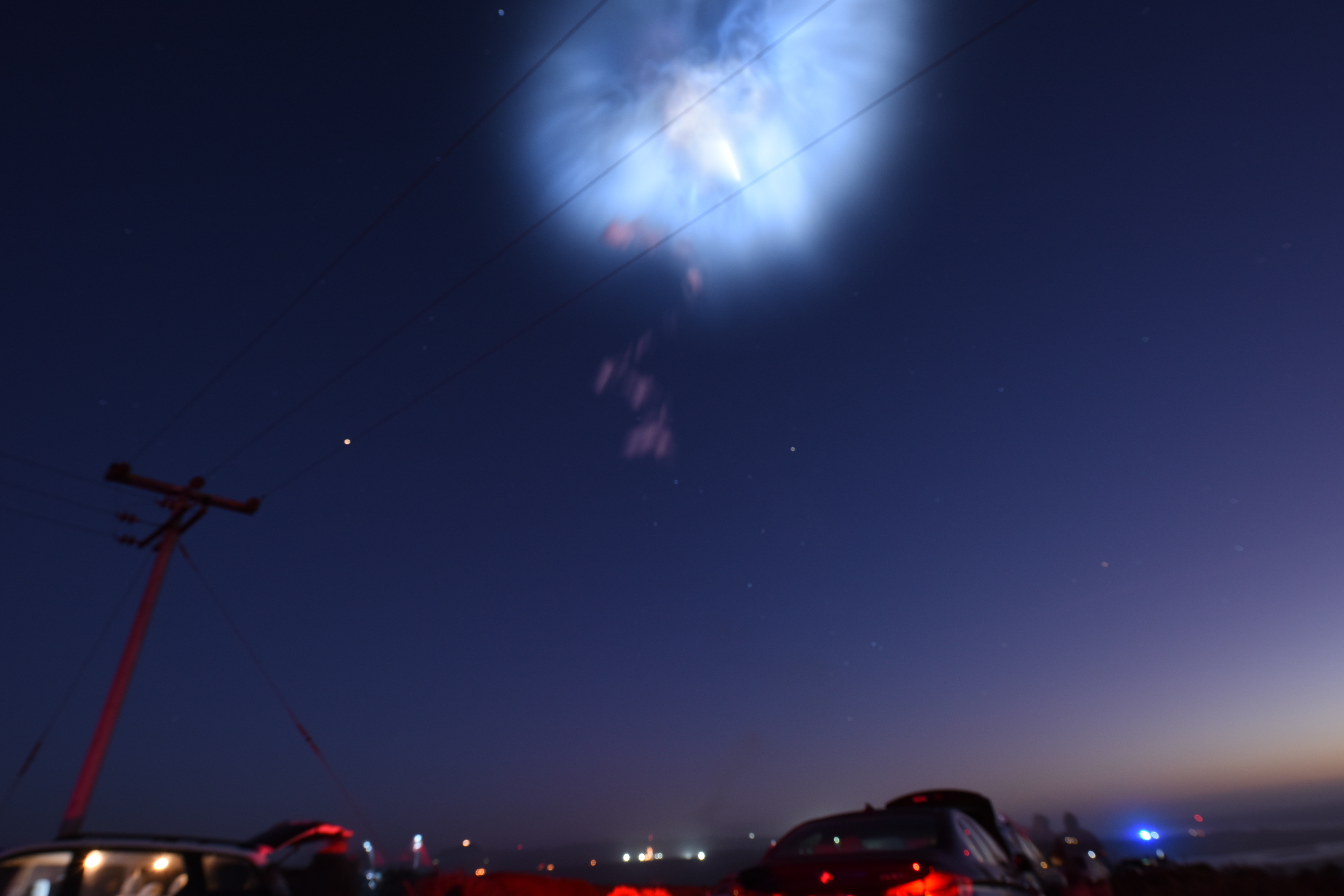 A Falcon 9 exhaust plume glowing as a space jellyfish at twilight