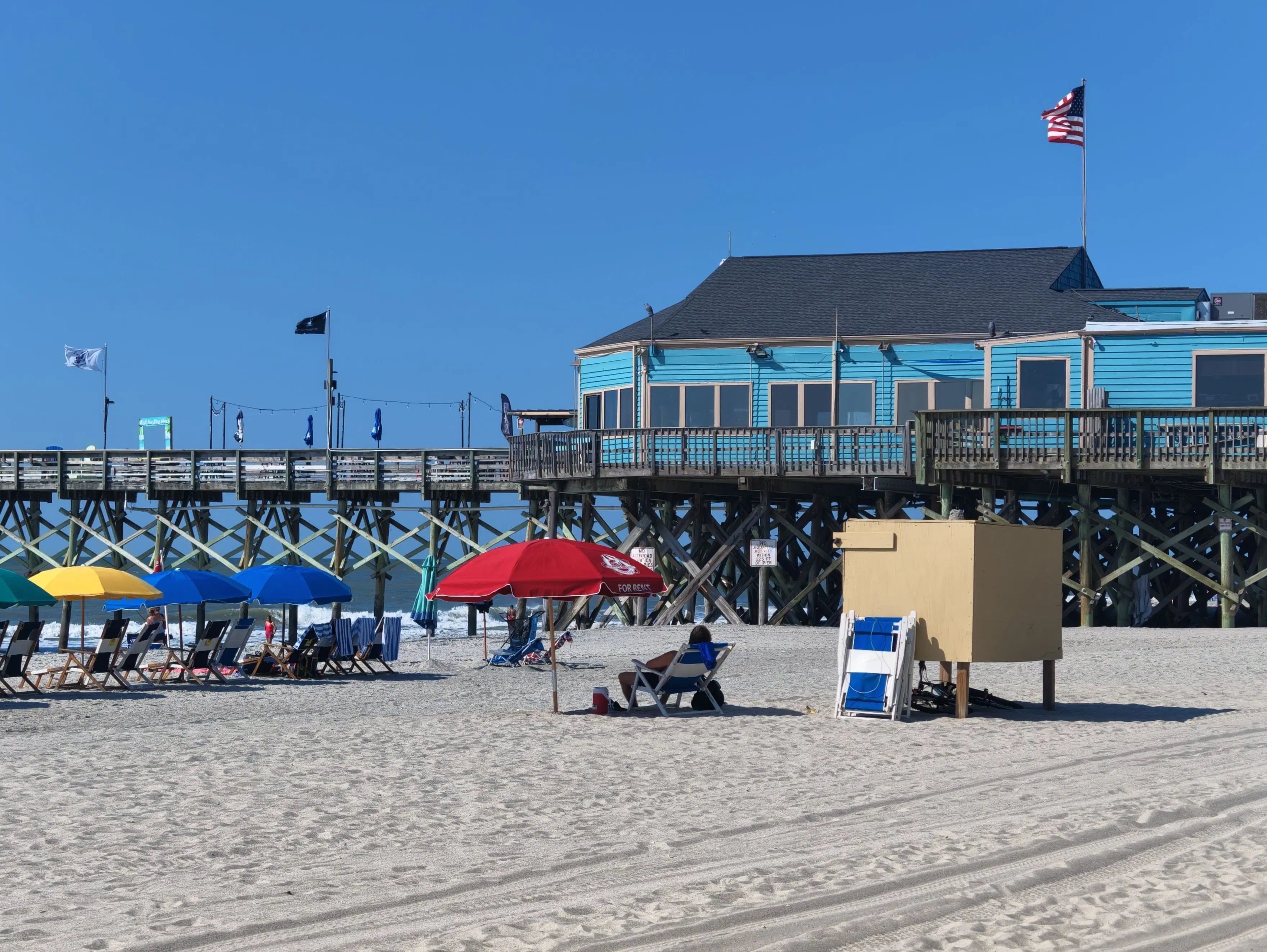 User-owned photo of beach umbrellas and chairs beside a pier